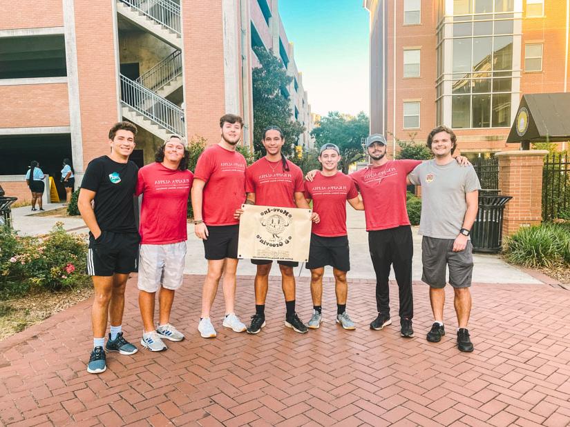 Group photo of fraternity students posing with a banner for fall 2023 move-in days.